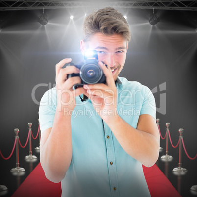 Composite image of handsome young man holding digital camera