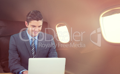 Composite image of happy businessman using laptop at table
