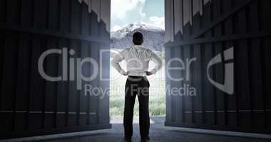 Composite image of businessman standing back to the camera with hands on hips 3d