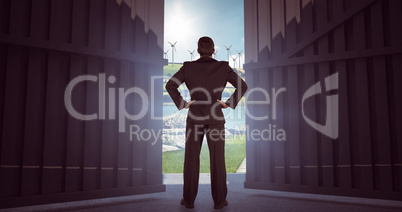 Composite image of businessman standing back to the camera with hands on hip  3d