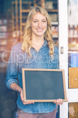 Smiling owner holding open signboard in supermarket