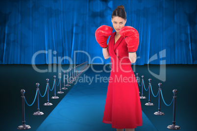 Composite image of elegant brunette in red dress wearing boxing gloves