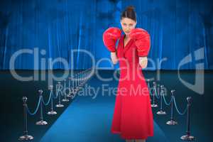 Composite image of elegant brunette in red dress wearing boxing gloves
