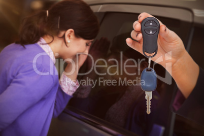 Composite image of woman holding key and small car