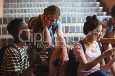 Classmates sitting on staircase and using mobile phone