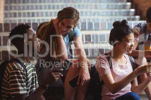 Classmates sitting on staircase and using mobile phone