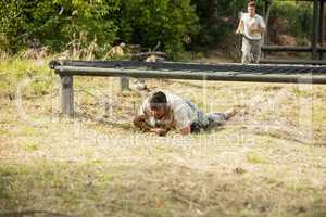 Soldier crawling under the net during obstacle course