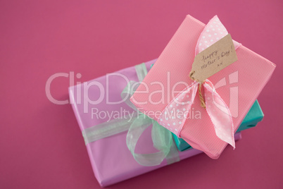 Gift boxes with happy mother day tag against pink background