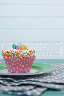 Cupcake with Easter eggs served in plate on a napkin