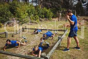 Fit people crawling under the net during obstacle course