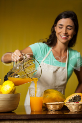 Female staff pouring juice into glass at counter