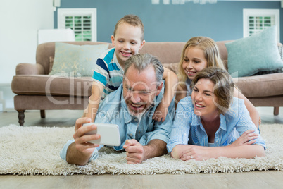 Family taking selfie while lying together on the carpet