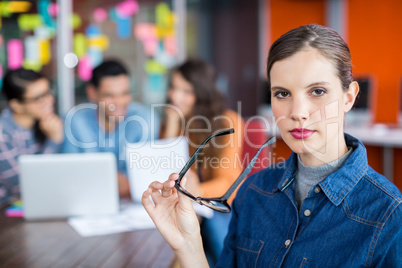 Portrait of female executive standing with spectacles