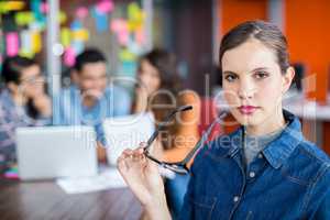 Portrait of female executive standing with spectacles