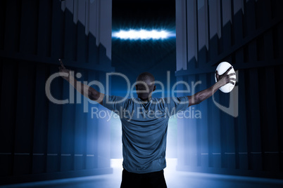 Composite image of rear view of sportsman with arms raised holding rugby ball 3d