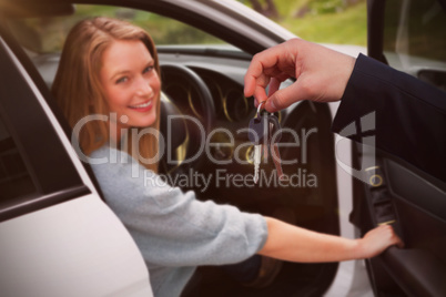 Composite image of couple receiving car keys by a dealer