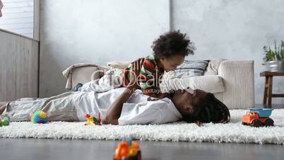 Father bonding with toddler son lying on carpet