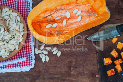 piece of pumpkin and pumpkin seeds on a brown wooden table