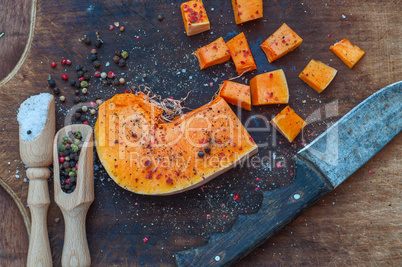 piece of pumpkin with spices is cut into cubes on a kitchen boar