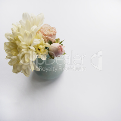 Bouquet of chrysanthemums and roses in a blue vase.