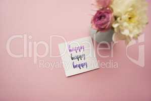 Happy written in calligraphy style on paper with bouquet of pink roses and white chrysanthemums on a pink background. Flat lay, top view