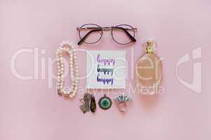 Happy handwritten with watercolor in calligraphy style. Women's fashion accessories arrangement on a pink background. Flat lay