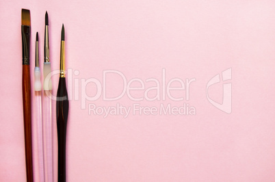 Paint brushes on a pink background with the place for your text. Top view