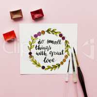 Inspirational quote do small things with great love , watercolor, brushes on a pink background. Artist workspace. Flat lay