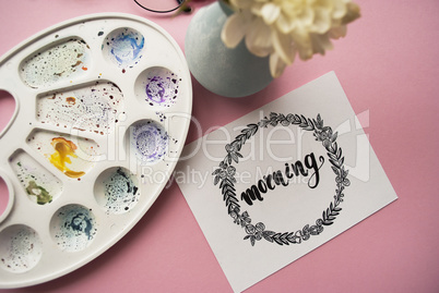 Morning written in calligraphy style with hand drawn floral wreath with bouquet of white chrysanthemums on a pink background. Top view