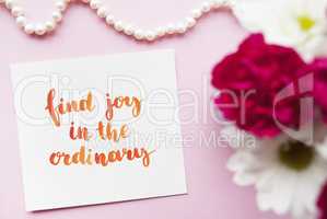 Inspirational quote Find joy in the ordinary written in calligraphy style with watercolor. Composition on a pink background. Flat lay