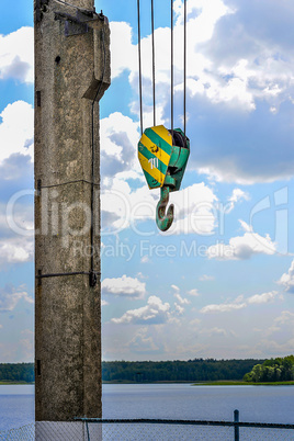 Yellow-green hook of a construction crane on a rope on a background of clouds