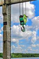 Yellow-green hook of a construction crane on a rope on a background of clouds