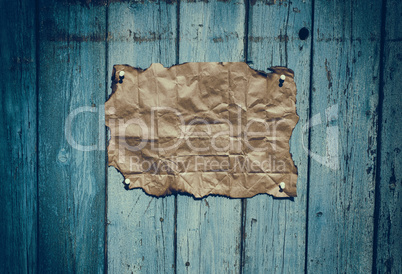 Brown rumpled kraft paper hanging on a blue wooden surface