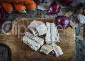 Pork pieces of bacon in salt on the kitchen cutting board