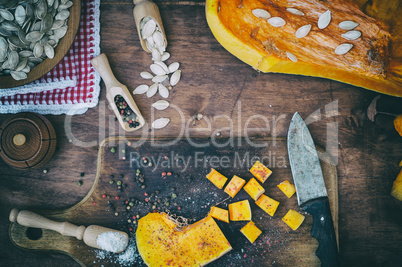 Pieces of pumpkin in salt and pepper on a kitchen cutting board