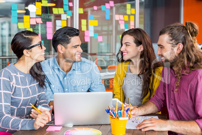 Smiling graphic designers discussing over laptop in meeting