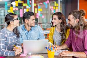 Smiling graphic designers discussing over laptop in meeting