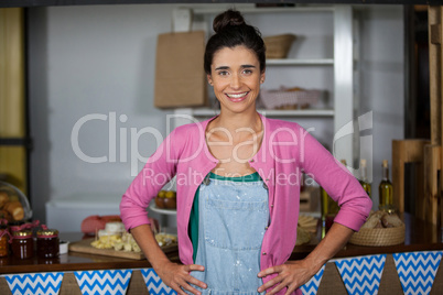 Portrait of smiling female staff standing with hands on hip