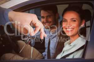 Composite image of smiling woman receiving keys from somebody