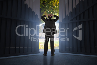 Composite image of businessman standing back to the camera with hands on head 3d