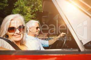 Old couple in a car smiling at camera