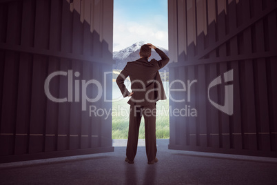 Composite image of businessman standing back to the camera with hand on head 3d