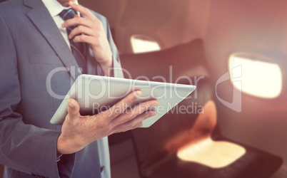 Composite image of midsection of businessman holding tablet computer