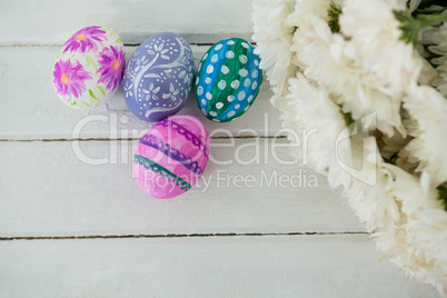 Multicolored Easter eggs and bunch of flower on wooden background
