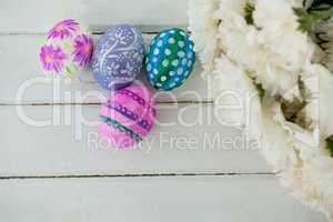 Multicolored Easter eggs and bunch of flower on wooden background