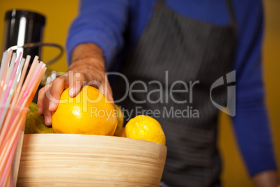 Mid-section of male staff holding lemon fruit at organic section