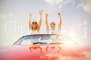 Crazy couple standing in red cabriolet