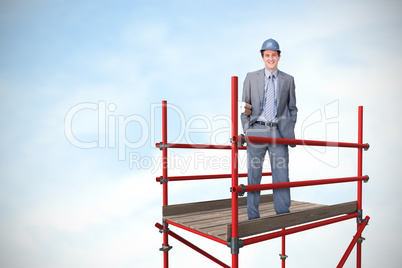 Composite image of smiling attractive architect on phone holding plans 3d