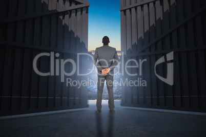 Composite image of young businessman standing with hands behind back 3d