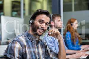 Portrait of male customer service executive talking on headset at desk